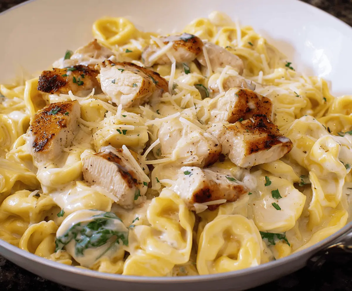 Creamy Chicken Tortellini Alfredo served on a white plate, garnished with fresh herbs and Parmesan cheese.