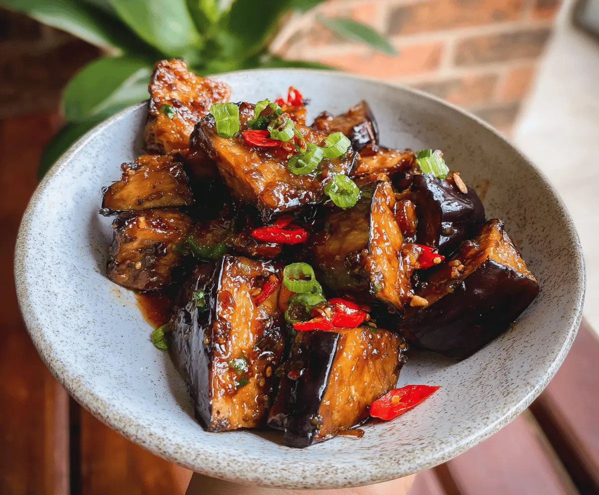 Delicious sticky garlic eggplant dish topped with fresh herbs, showcasing crispy edges and glossy sauce, perfect for flavorful vegetarian meals.