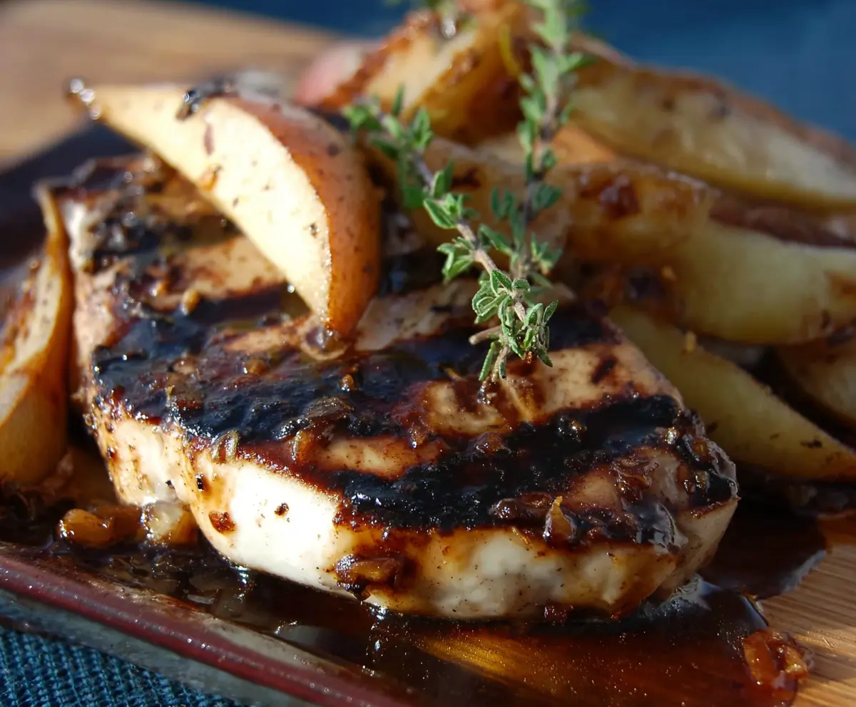 Delicious grilled pork chops served with balsamic caramelized pears on a plate.