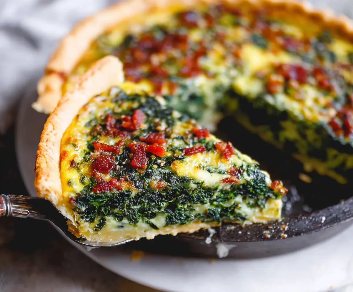 Delicious spinach quiche with crispy bacon slices on top, perfect for brunch or lunch.