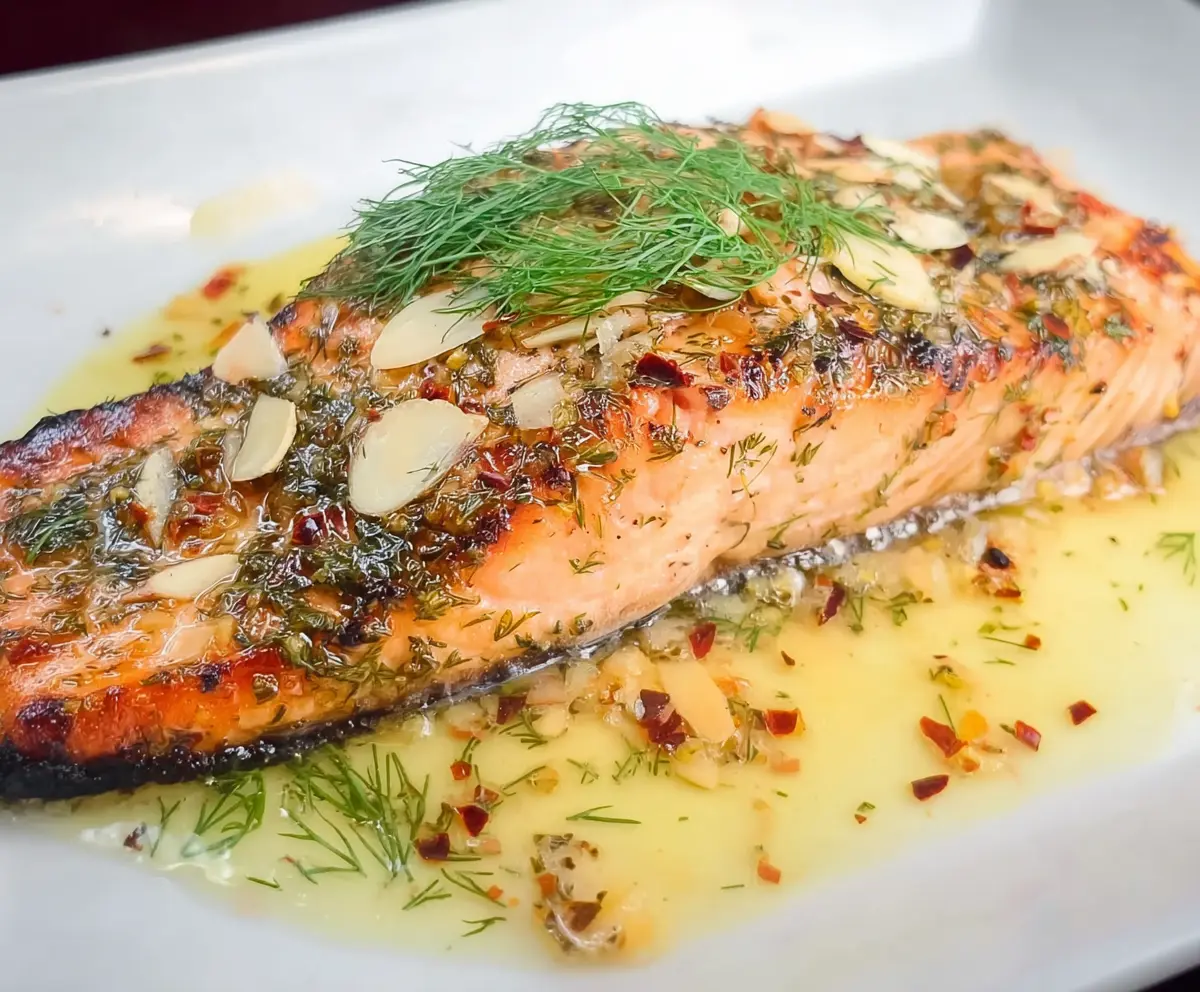 Delicious Lemon Dill Salmon topped with garlic, served with white wine and butter sauce on a elegant plate.